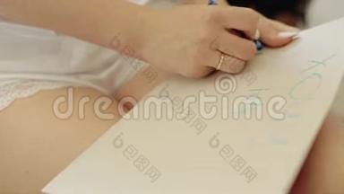 那个女孩用铅笔在一张纸板上写字。 显示女孩`的手特写。 友谊的交流。